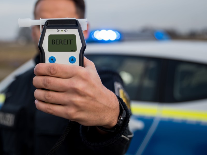 Ein Polizist hält ein Alkoholtest-Gerät in die Kamera.