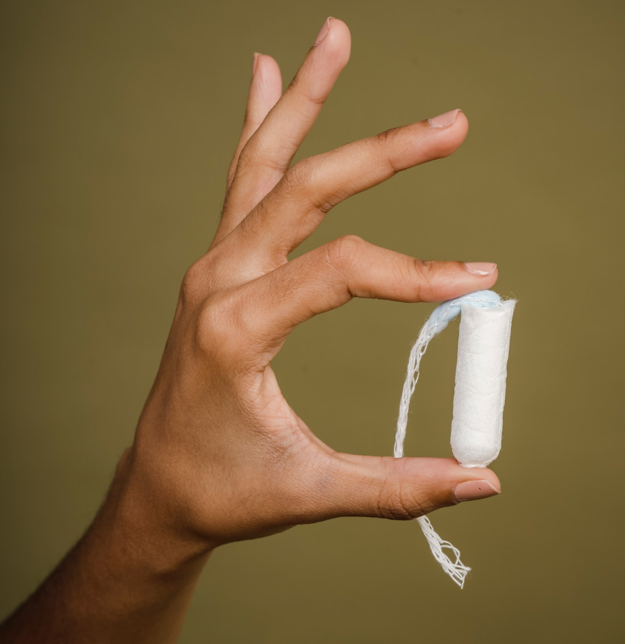 Eine Hand hält einen Tampon zwischen Daumen und Zeigefinger