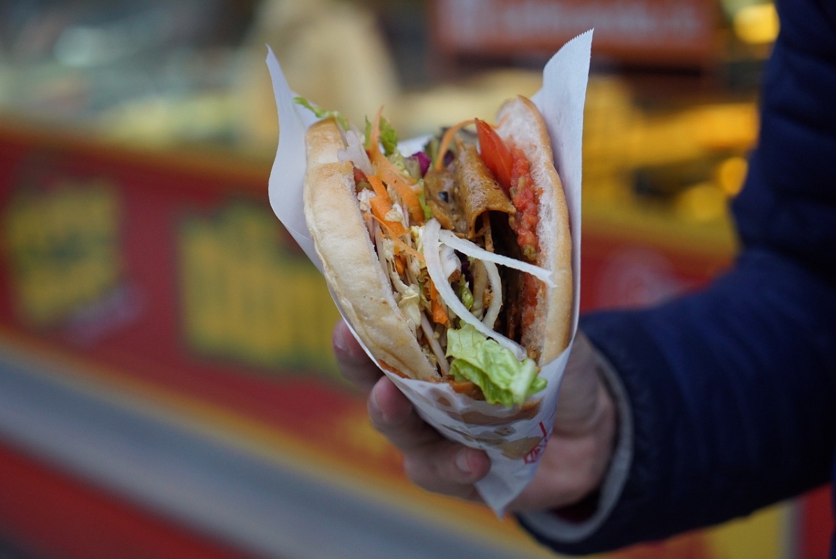 Ein Mann hält einen Döner Kebab in der Hand.