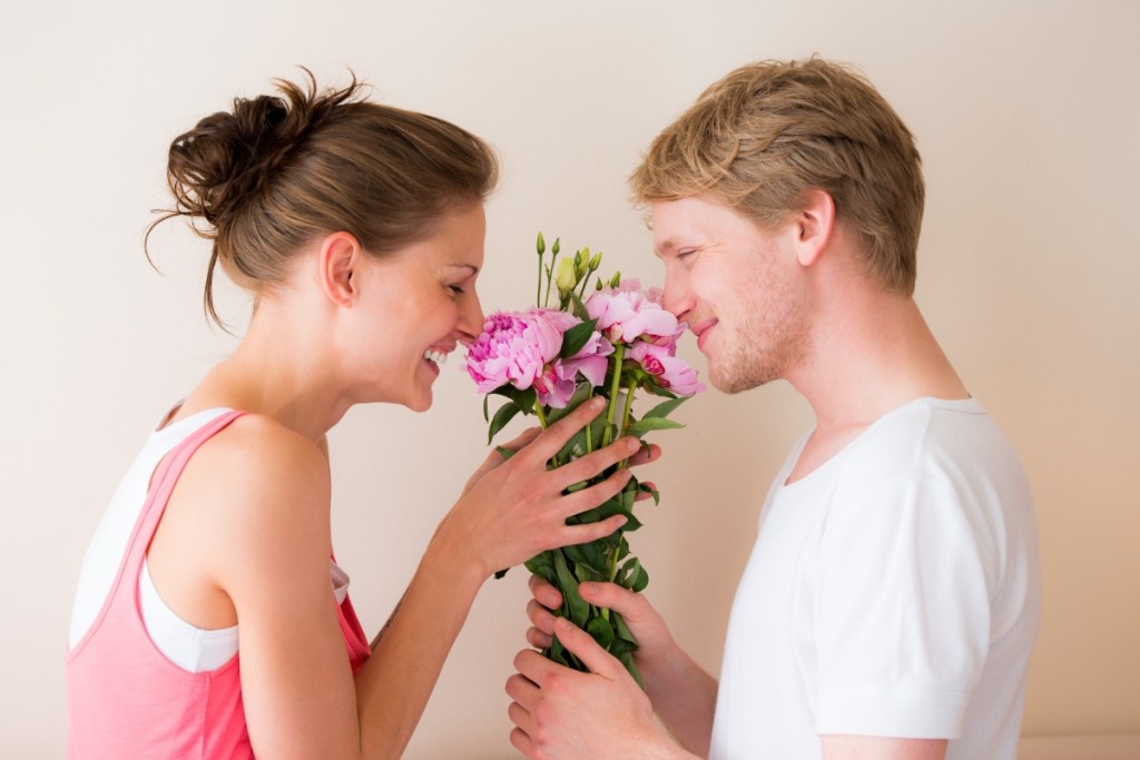 Ein verliebter junger Mann schenkt seiner Frau einen Blumenstrauß Rosen.