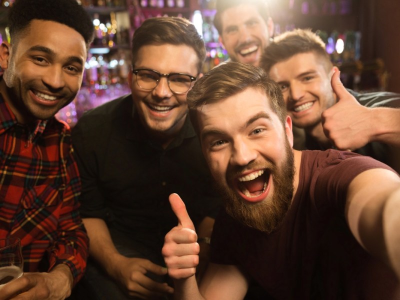 Gut gelaunte Freunde machen ein Selfie in einer Kneipe.