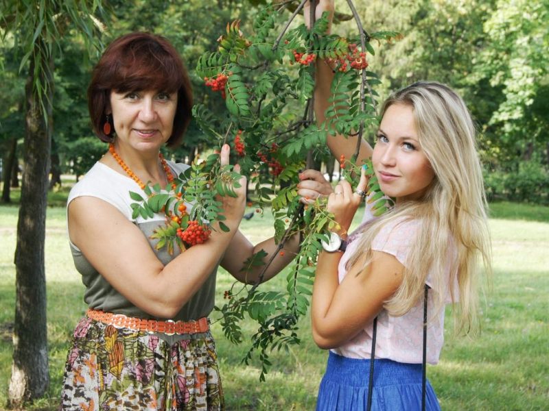 Eine Mutter hält mit ihrer blonden Tochter einen geflochtenen Kranz in den Händen.