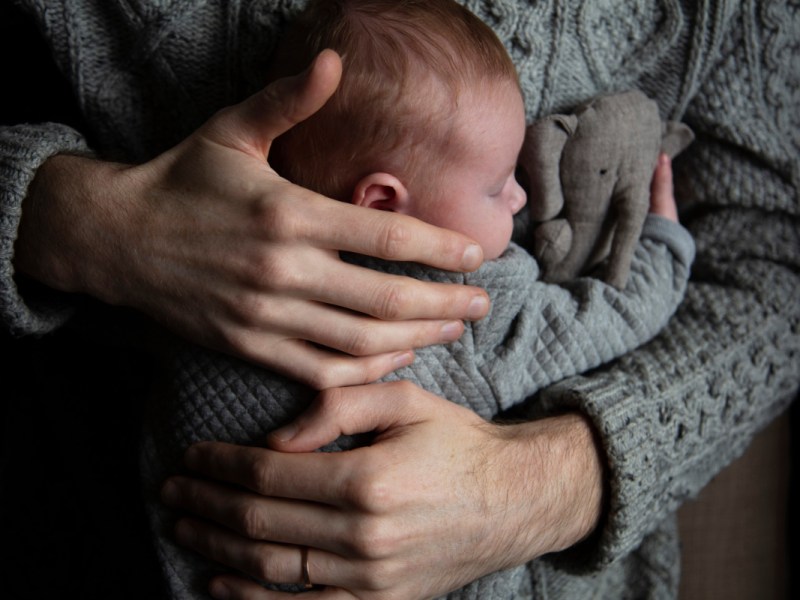 Ein Mann umarmt ein Baby, das ein Kuscheltier festhält.